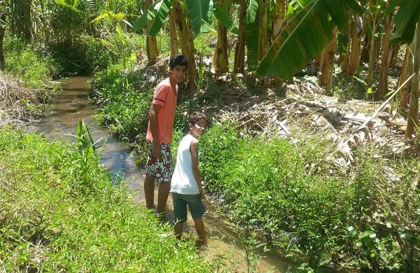 Zwei Kinder an einem kleinen Flußlauf auf der Nòs na Vida Farm.